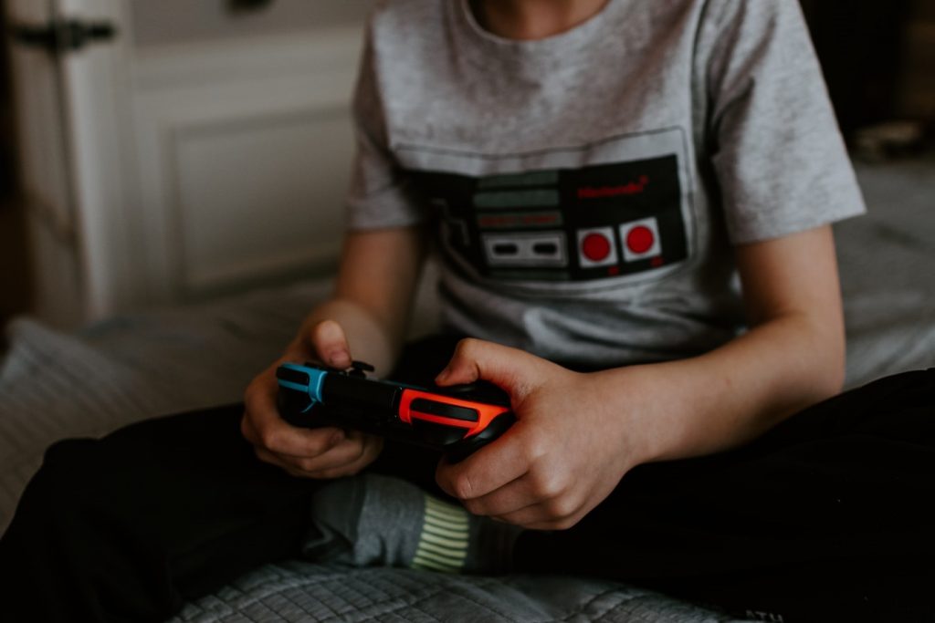 Uma criança brincando com seu videogame como uma forma de passatempo.
