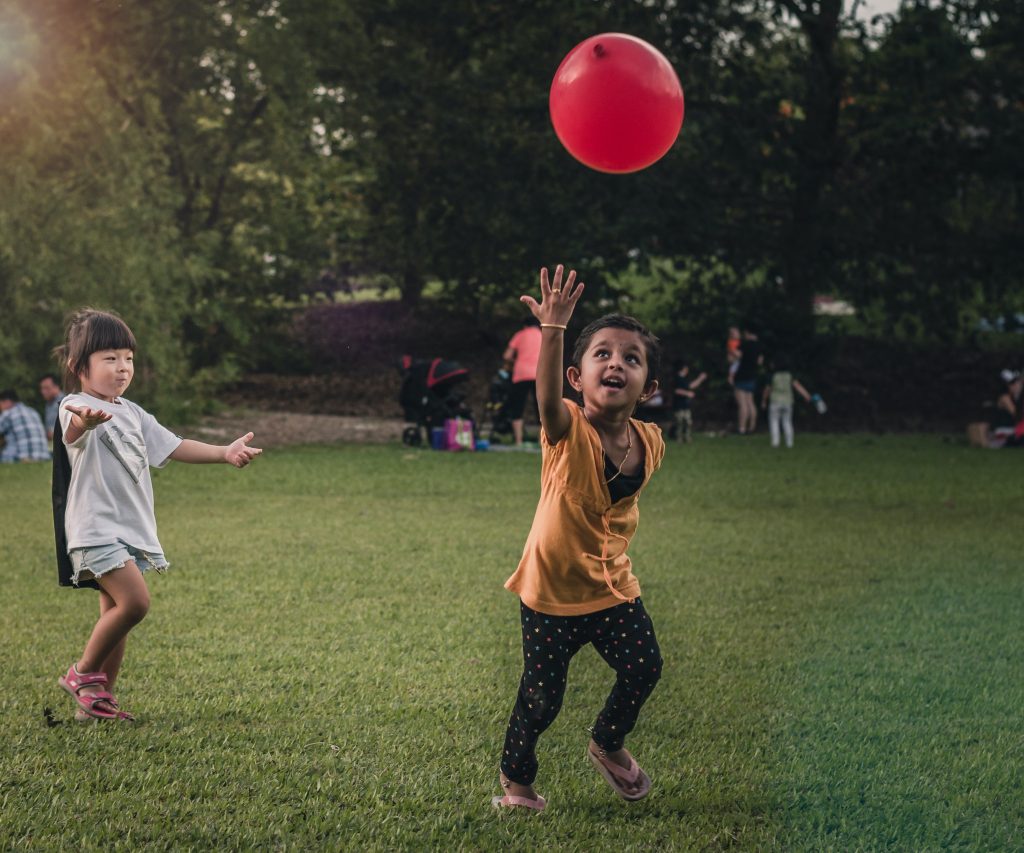 Crianças brincando com uma bola vermelha.