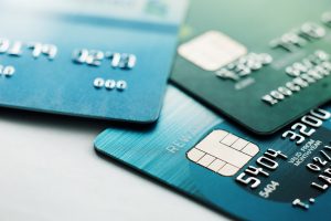 Imagem de uma mesa com três cartões de crédito sobre ela, dois azuis e um verde, a imagem simboliza a ideia de ganhar dinheiro com cartão de crédito.